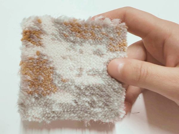 高密度のカーペットのサンプルを触る
