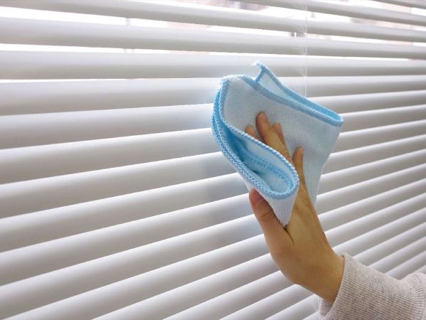 ブラインドを布で拭き取っている