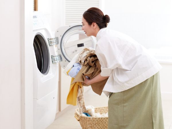 洗濯物をドラム式洗濯機に入れようとする女性