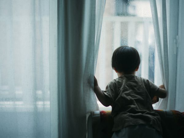 雨降りの外を眺める子供