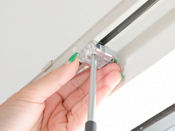 カーテンレールに通したブラケットをネジで固定している
