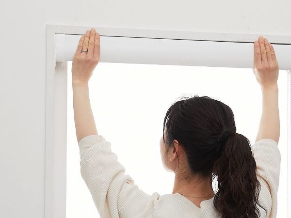 つっぱり式ロールスクリーンが固定されているか確認している