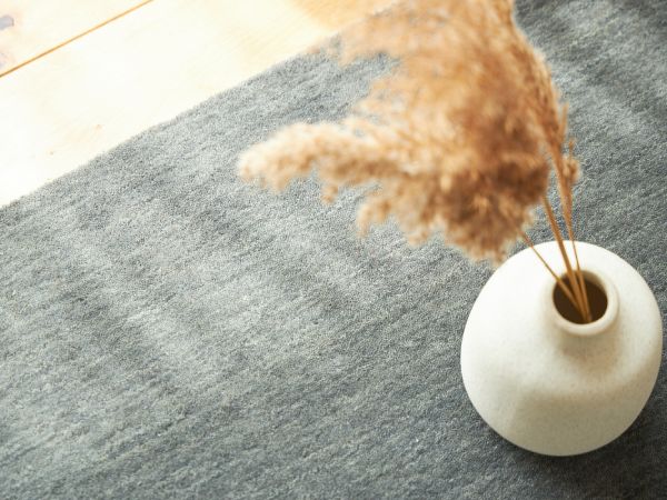 グレーのラグに陶器の花瓶が置かれている