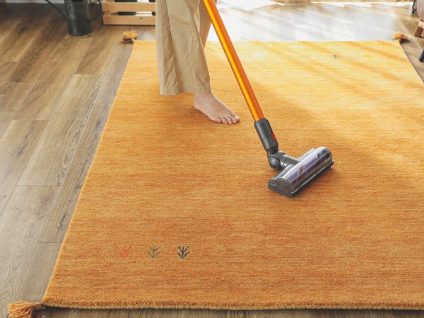 ウールラグを掃除機掛けする女性