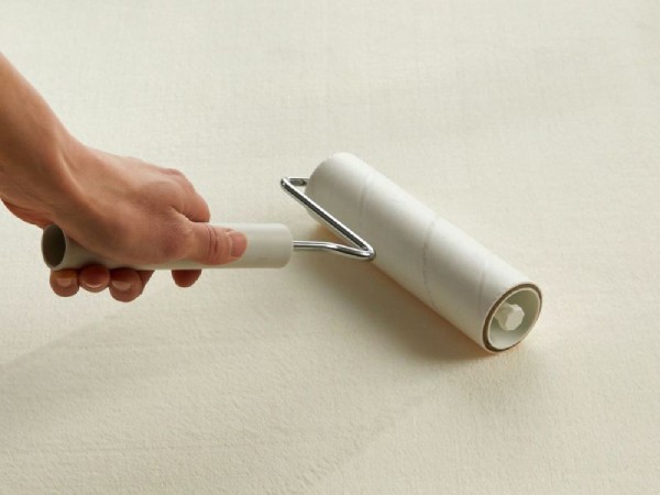 ラグ『ホリデープラス』にコロコロを掛けて掃除している