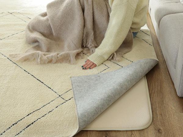 薄いラグにクッション材となる中敷きを敷いている様子