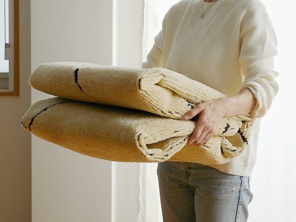 洗濯できて持ち運びのしやすいラグと女性