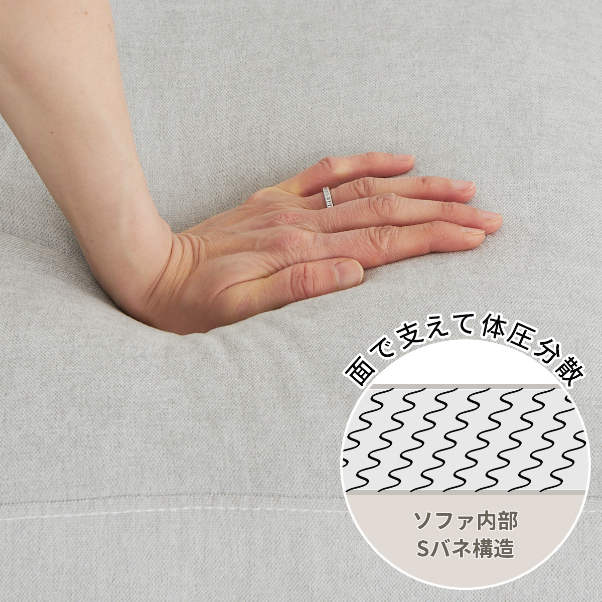 グレーのソファの座面を手で押しているカット