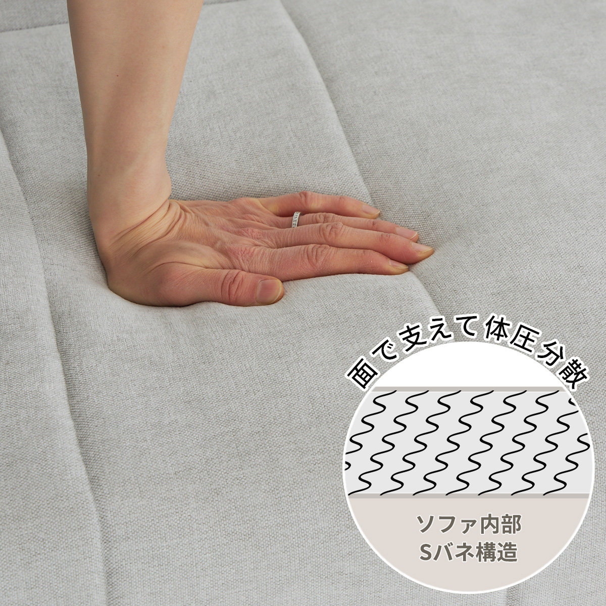 グレーのソファの座面を手で押しているカット